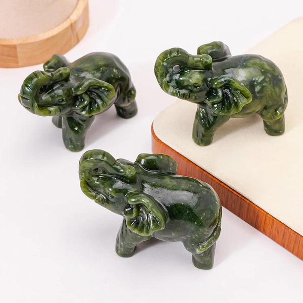 Hand-carved green jade elephant statue for home decor resting on a light wooden surface.