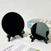 A black obsidian scrying mirror decor is shown on a stand next to its packaging box.