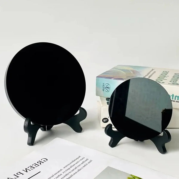 A black obsidian scrying mirror decor is shown on a stand next to its packaging box.