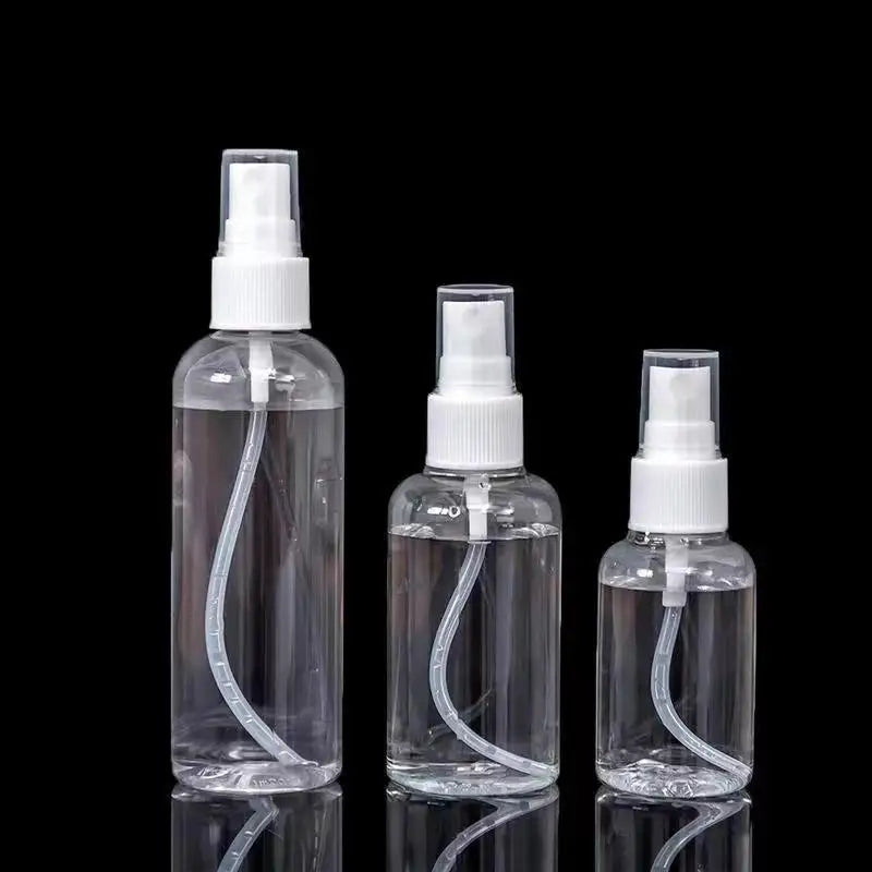 Clear refillable portable spray bottles standing vertically against a black background
