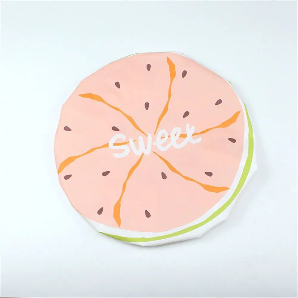 A pink citrus fruit slice design on a white background for a reusable fruit shower cap.