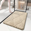 A beige plush non-slip bathroom rug is shown on a white marble floor next to a glass panel.