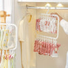 A white multi-clip drying rack hanging on a rod, displaying various pink and white baby clothes and accessories.