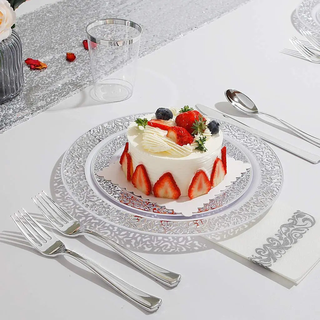 Weißer Kuchen mit Erdbeeren und Sahne auf silbernem Teller, auf weißem Tisch serviert.