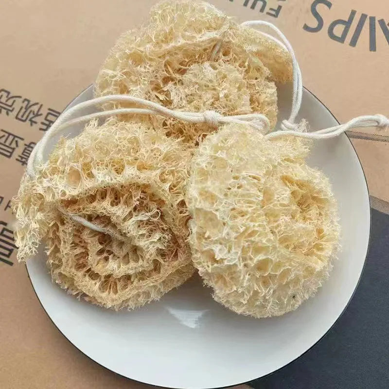 A pile of natural loofah exfoliating body sponges tied with white rope on a white plate.
