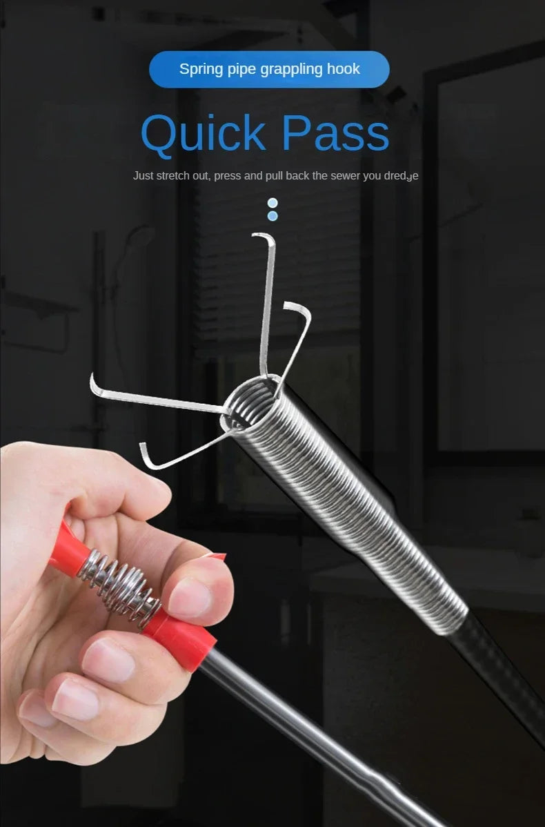 A hand is using a spring pipe grappling hook tool to clear a drain or sink blockage.