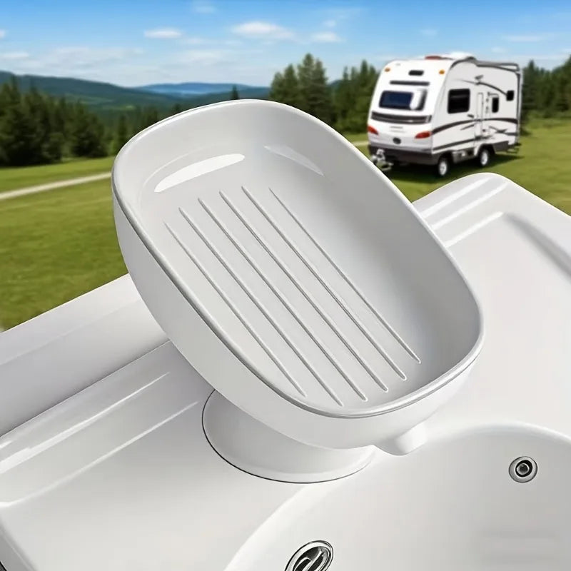 A white countertop soap dish with a slotted design is shown resting on its suction cup base.