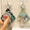 A hand is hanging a green and black Totoro cartoon-themed towel onto a wall hook.