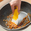 A hand uses a yellow silicone kitchen scraper to stir food in a dark cooking pan.