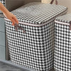 Une main ouvre un sac de rangement pour vêtements pliable et anti-poussière à motif noir et blanc à carreaux.