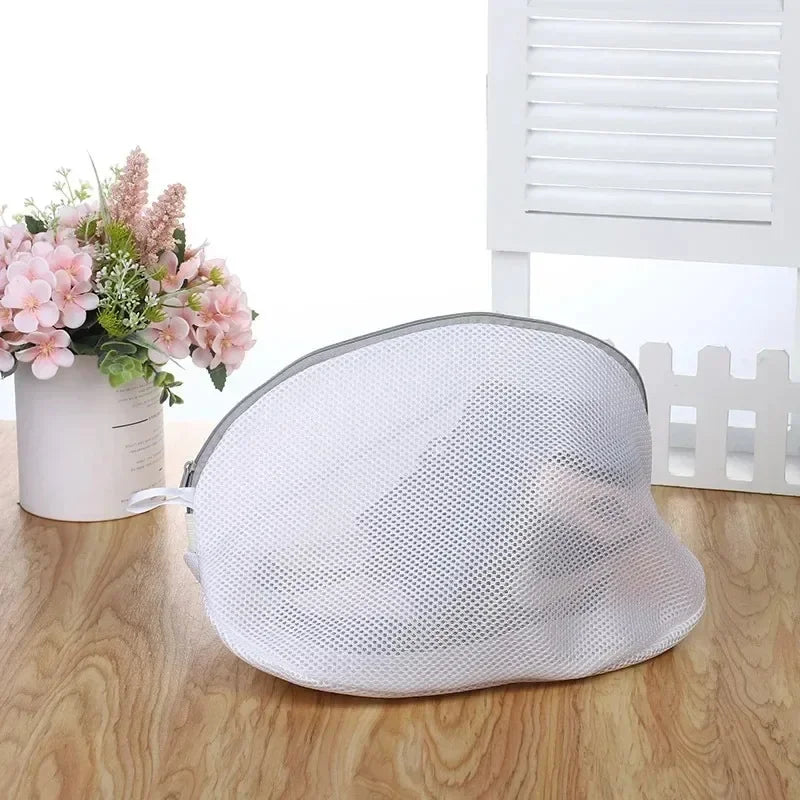 A white mesh laundry bag for shoes and delicates with a zipper resting on a wooden surface.