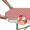 A hand is placing a red and white plaid tablecloth onto a gray table.