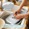 A hand is using a silicone fabric washing board to clean items in a sink.