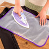 Hands are ironing a garment using a purple and white iron on a grey ironing protection mesh pad.