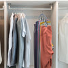 Una fila de camisas y chaquetas colgadas en un rack de secado de perchas de acero inoxidable con organizador de clips múltipl