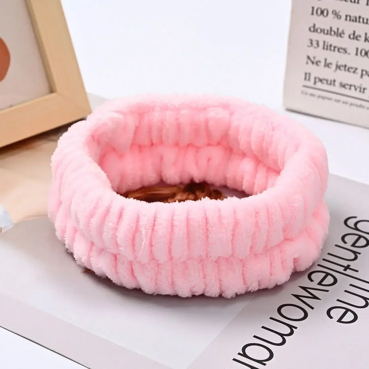 A pink microfiber wrist sweatband set for face washing and skincare is shown on a white surface.