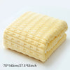 A stack of yellow luxury coral velvet bath towels folded neatly on a white surface.