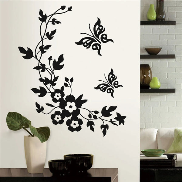 Black silhouette botanical leaf wall sticker featuring floral and butterfly designs on a white wall.