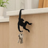 Black monkey shaped wooden key hanger decoration mounted on a light wood cabinet