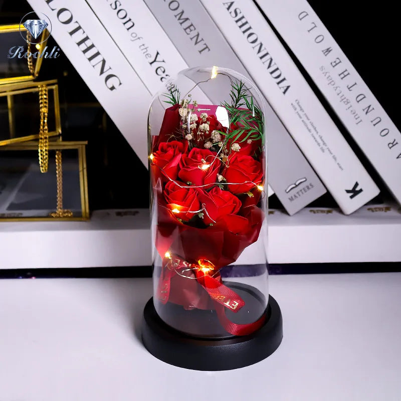 Glasvase mit roten Rosen und Grün, beleuchtet durch LED-Lichter.