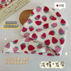 A pink and white strawberry print quick-drying hair towel headscarf is shown folded next to a wooden tray.