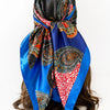 A vibrant blue scarf featuring an intricate paisley print with orange, red, and black patterns tied around dark hair.