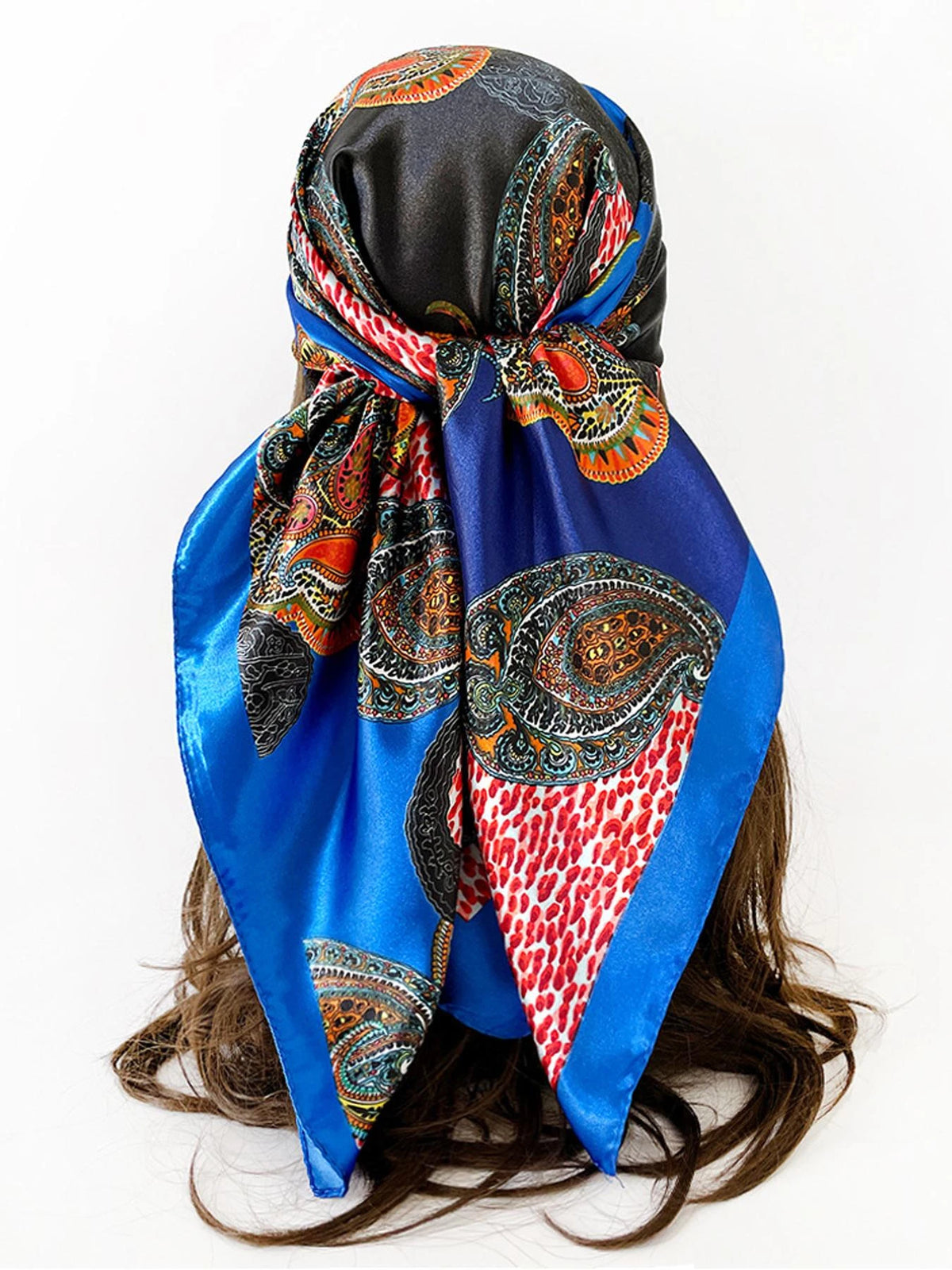 A vibrant blue scarf featuring an intricate paisley print with orange, red, and black patterns tied around dark hair.