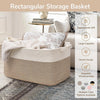 A rectangular woven storage basket in beige fabric sits on a gray rug next to a sofa.