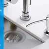 A close-up of a modern stainless steel under-sink kitchen soap dispenser with a chrome faucet and a circular dish.