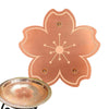 A copper bird bath disk with a floral design and triple-point support is shown next to its base.
