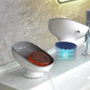 A white heavy duty suction cup soap dish with a drainer and an LED light is shown on a countertop.