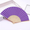 Ventilateur pliable violet à la main, fait de bambou et de papier avec un cadre en bois clair.