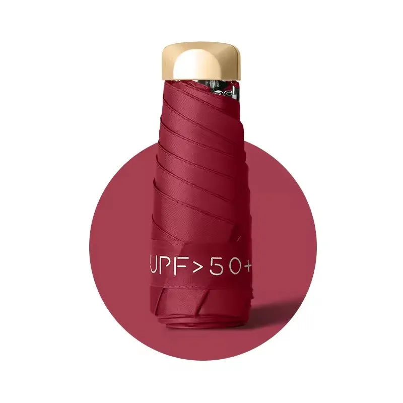 A compact folding UV protection umbrella with a gold-colored handle and a deep red fabric cover.