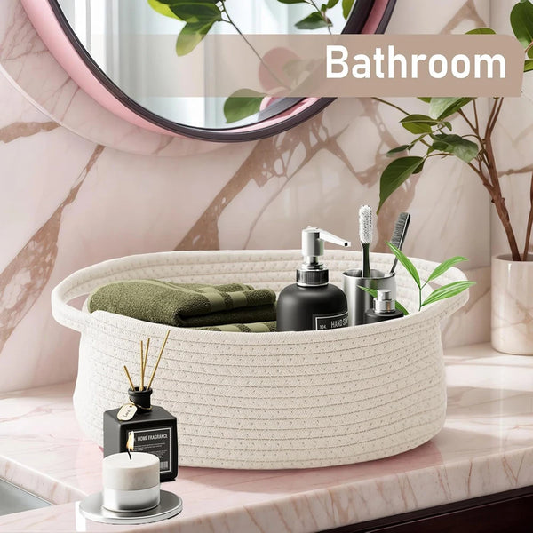 A white handwoven rope storage basket filled with green towels and toiletries on a marble countertop.