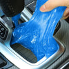 A hand is squeezing a bright blue gel kit for removing dust and debris from a surface.