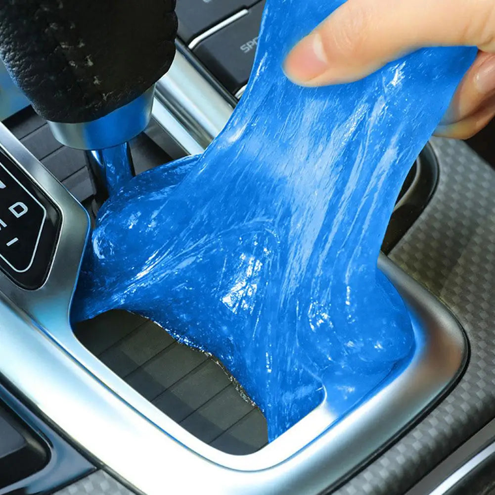 A hand is squeezing a bright blue gel kit for removing dust and debris from a surface.