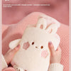 A pink fluffy bunny plush animal is being held by hands, set against a pink knitted background.