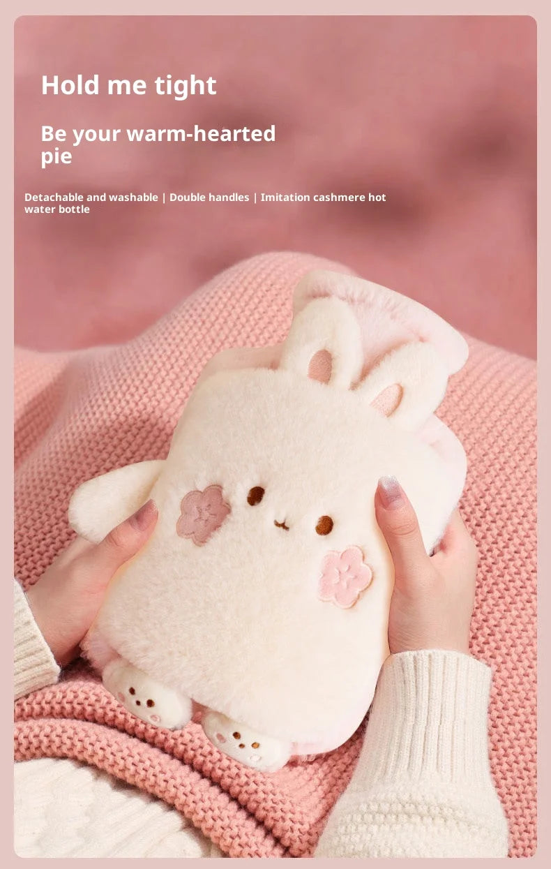 A pink fluffy bunny plush animal is being held by hands, set against a pink knitted background.