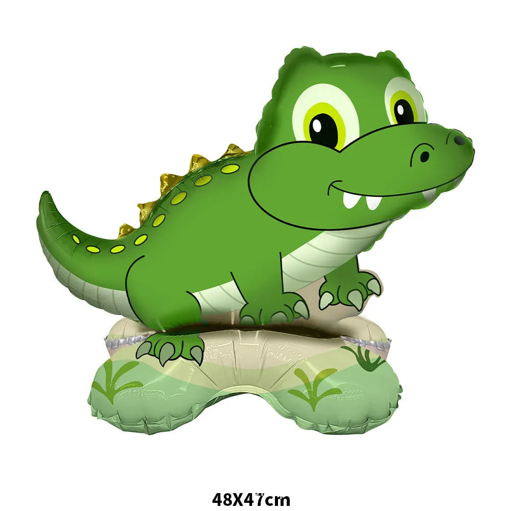 A green cartoon crocodile foil balloon with large eyes and teeth sitting on a green mat.