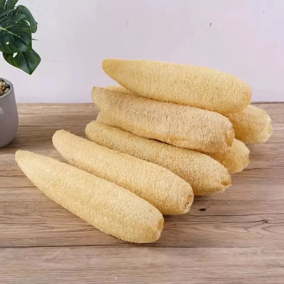 A stack of natural yellow loofah exfoliating body sponges with hanging ropes on a wooden surface.