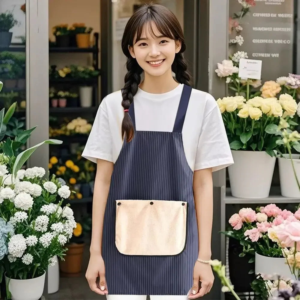 A young woman models a navy striped waterproof kitchen apron with a removable beige hand towel in a bright indoor setting.