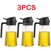 Three clear glass oil spray bottles with black pumps and yellow oil inside