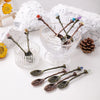 Natural crystal spoons with various colored crystals arranged on white rocks and glass bowls.