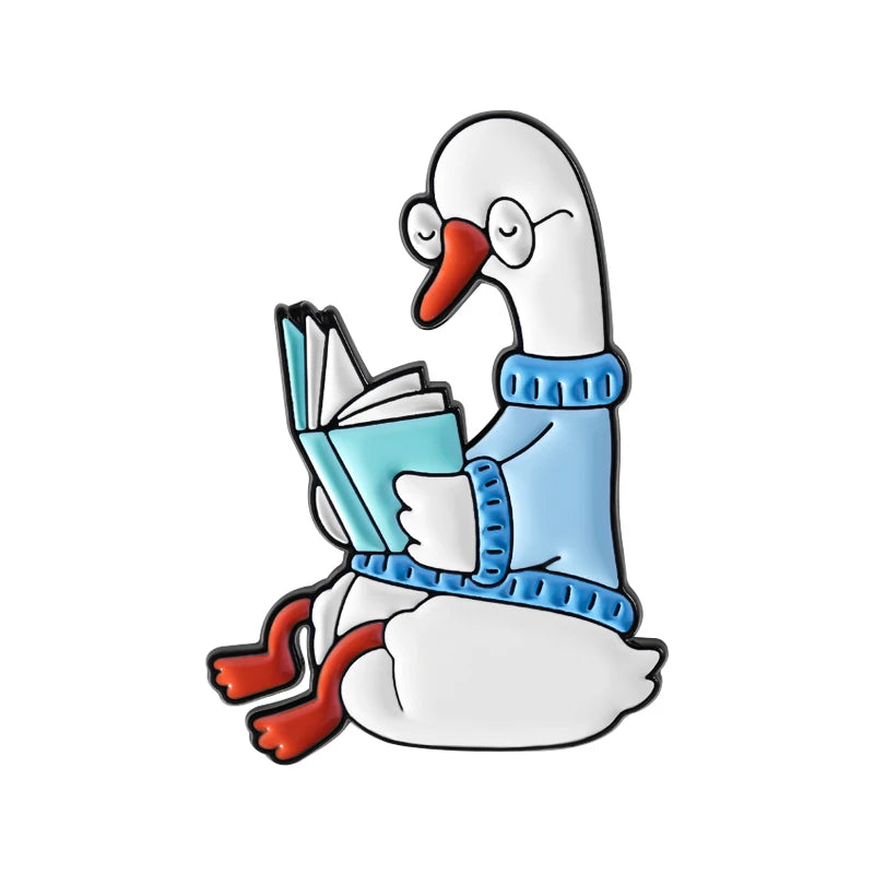 Un pato blanco con suéter azul sosteniendo un libro abierto, diseñado como pin de esmalte.