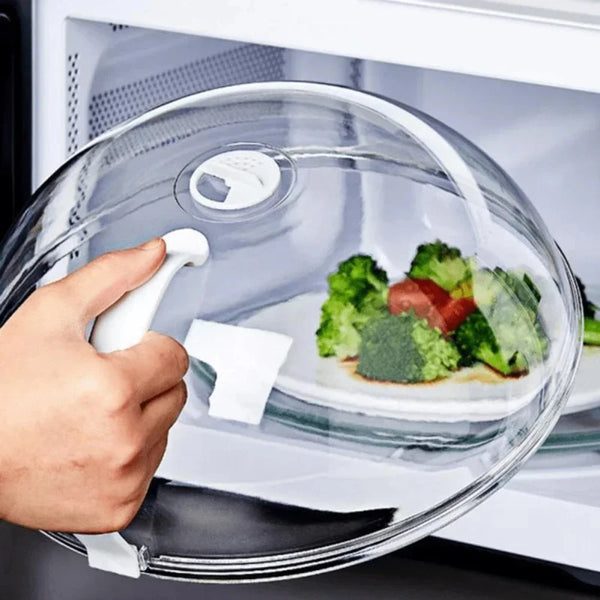 A hand is opening a clear splash guard designed to protect food in a microwave oven.