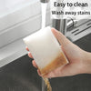 A hand is holding a translucent white melamine foam cleaning sponge under running water, demonstrating its ease of cleaning.