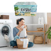 A woman sits in front of a washing machine with a box of Tumble Dryer Sheets and woven baskets.