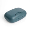 A smooth, oval-shaped, matte blue-gray portable travel soap box with a hinged lid.