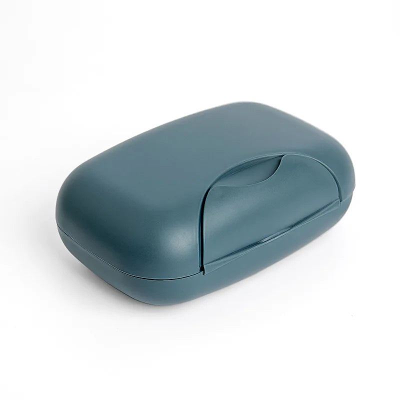 A smooth, oval-shaped, matte blue-gray portable travel soap box with a hinged lid.
