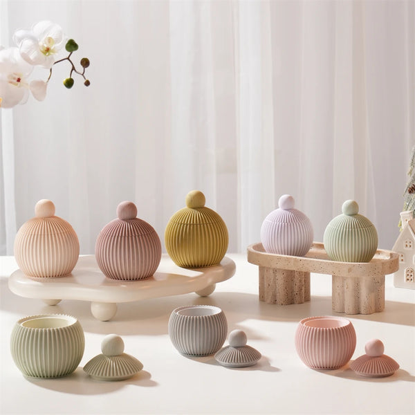 A collection of round silicone candle molds in various muted green and pink tones displayed on a white surface.